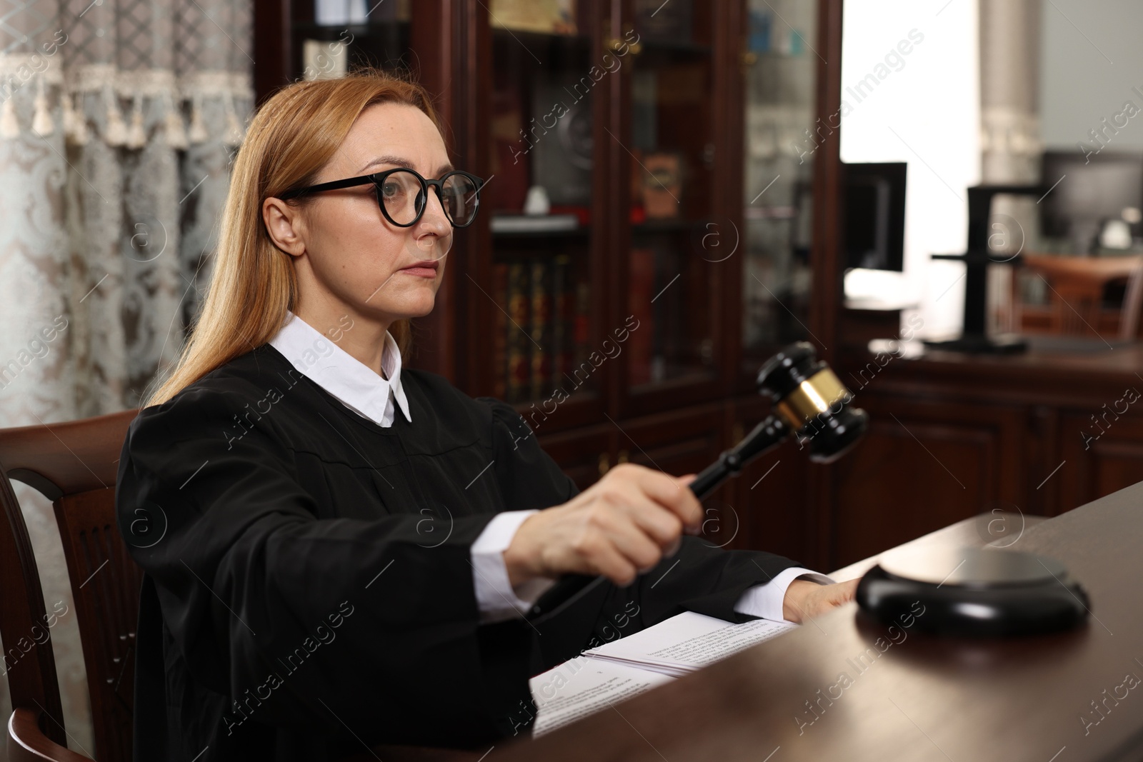 Photo of Judge striking gavel at table in courtroom