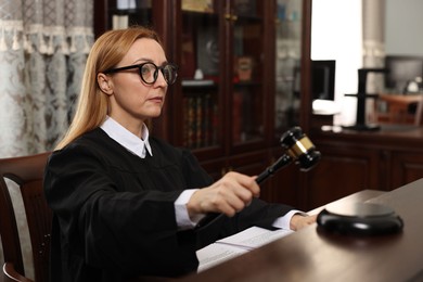 Photo of Judge striking gavel at table in courtroom