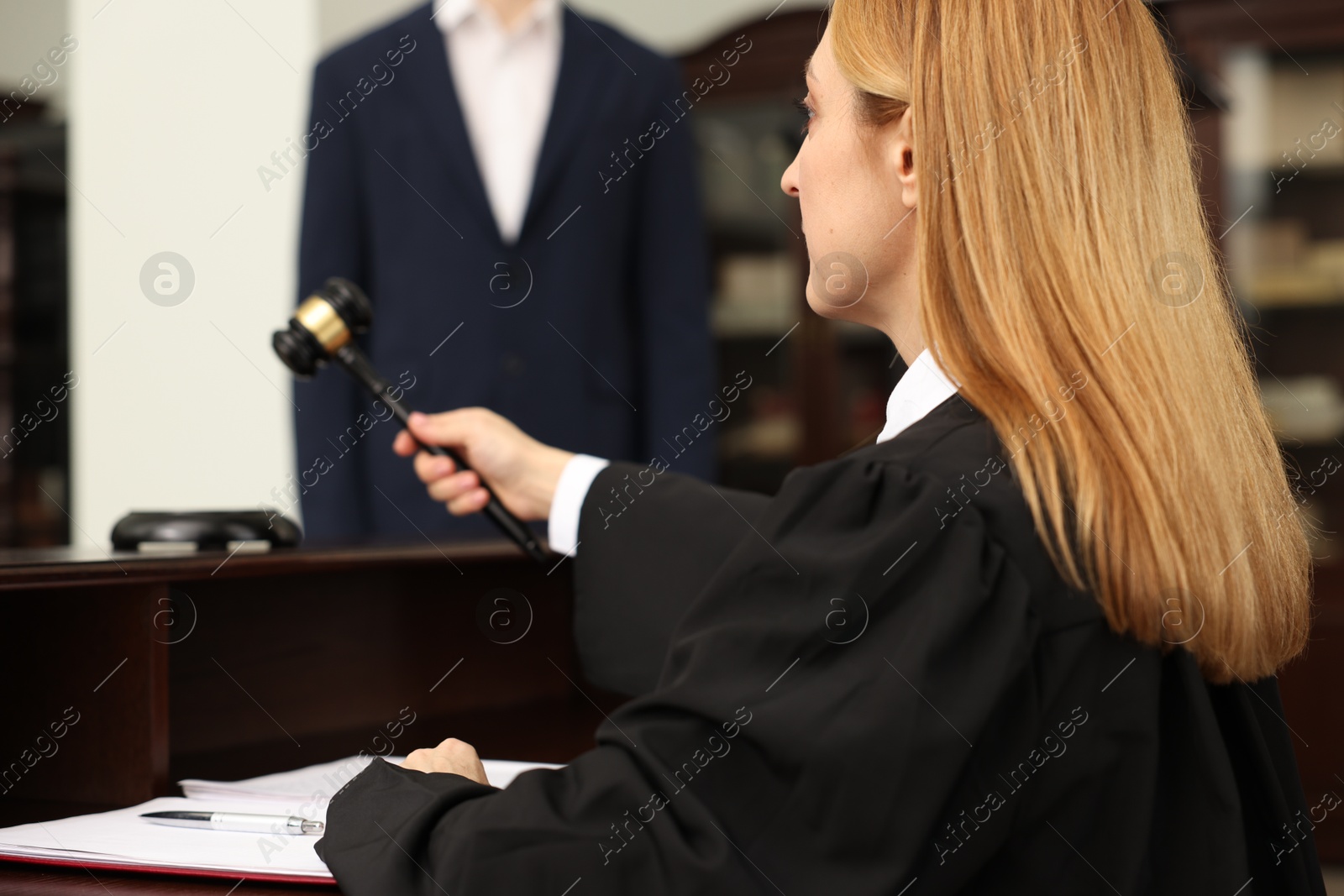 Photo of Judge striking gavel at table in courtroom, selective focus