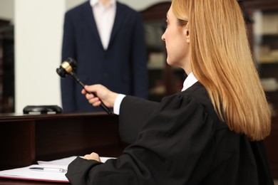 Photo of Judge striking gavel at table in courtroom, selective focus