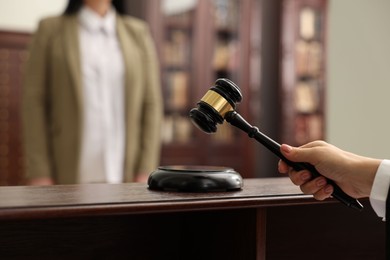 Photo of Judge striking gavel at wooden table in courtroom, closeup