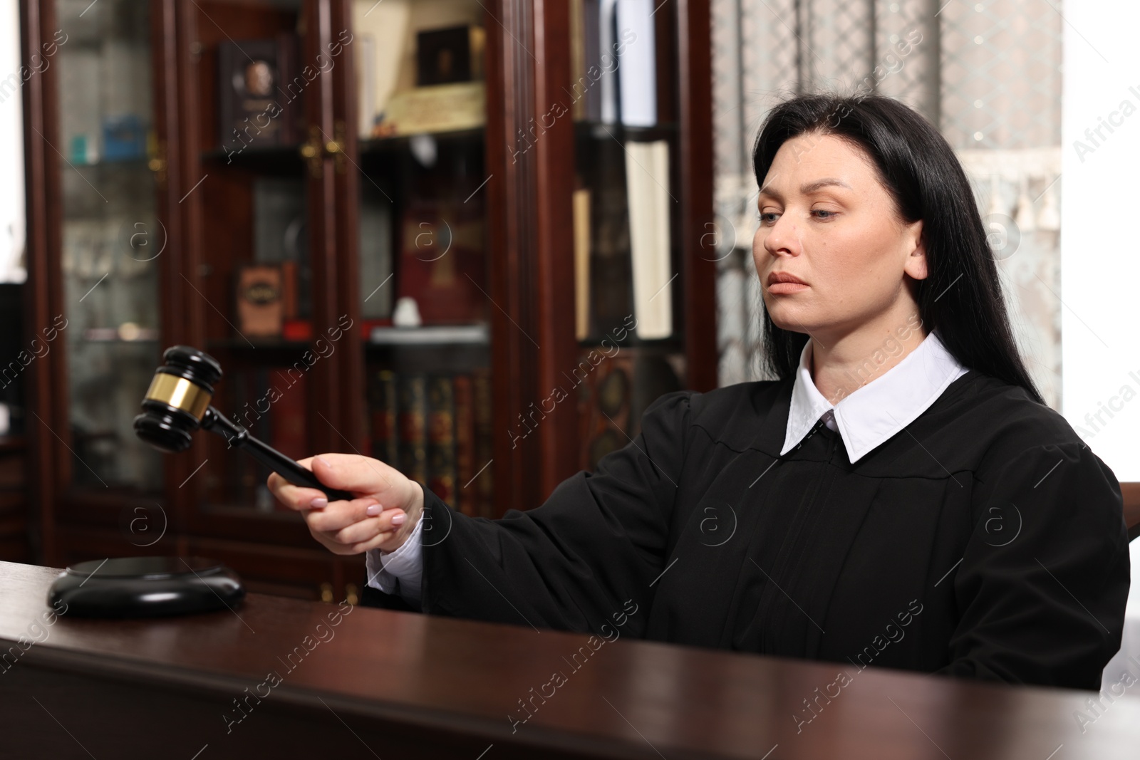 Photo of Judge striking gavel at wooden table in courtroom