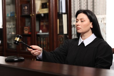 Photo of Judge striking gavel at wooden table in courtroom