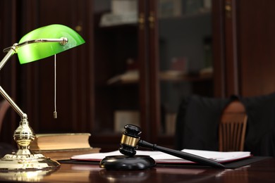 Photo of Judge workplace with gavel, lamp, documents and books in office