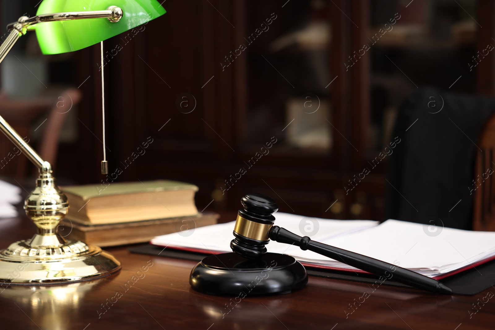 Photo of Judge workplace with gavel, lamp, documents and books in office