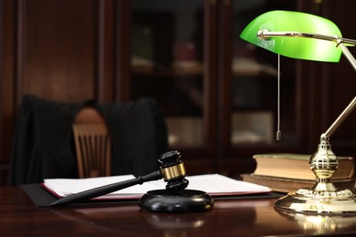 Photo of Judge workplace with gavel, lamp, documents and books in office