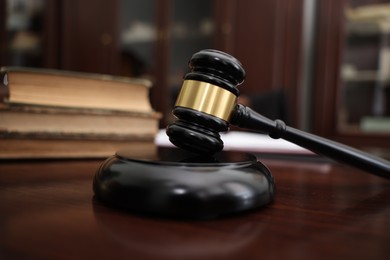 Photo of Judge workplace with gavel and books indoors, closeup