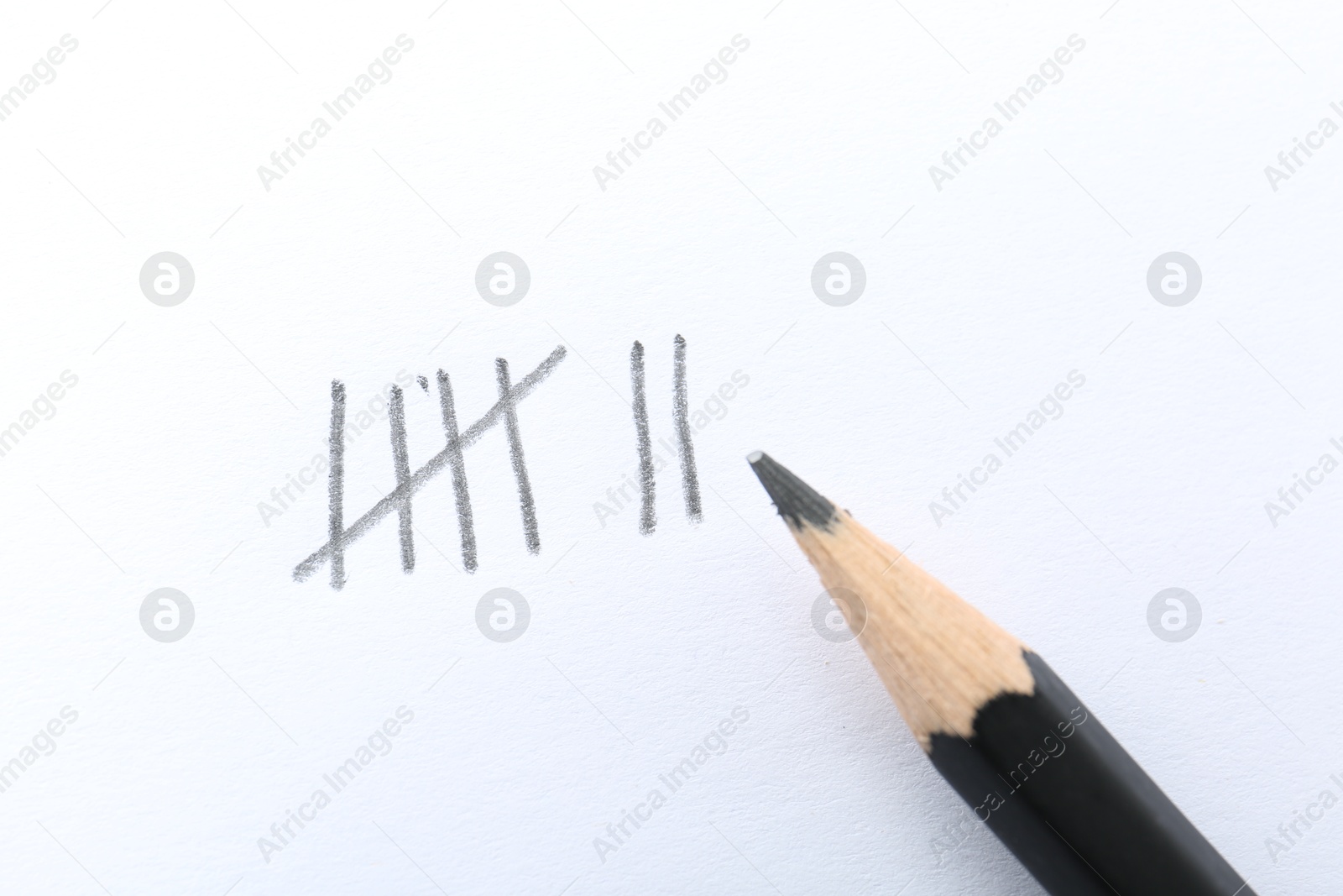 Photo of Counting days by drawing sticks with pencil on white background, closeup