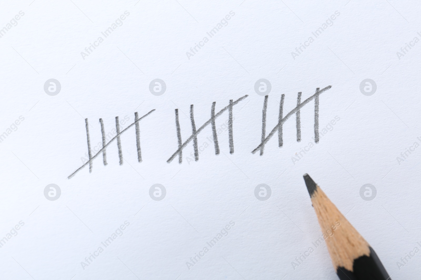 Photo of Counting days by drawing sticks with pencil on white background, closeup