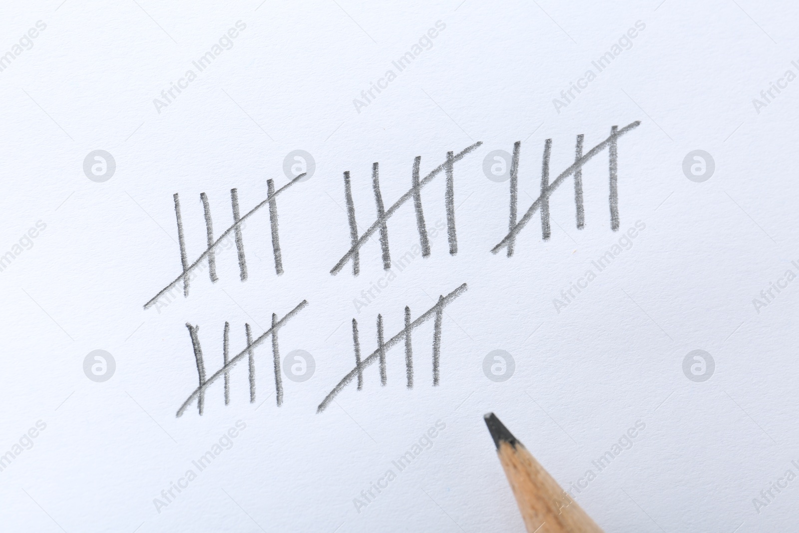 Photo of Counting days by drawing sticks with pencil on white background, closeup