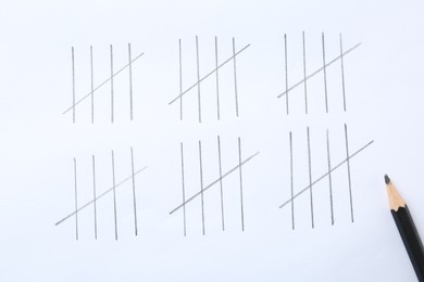 Photo of Counting days by drawing sticks with pencil on white background, closeup