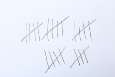 Photo of Counting days by drawing sticks with pencil on white background, closeup