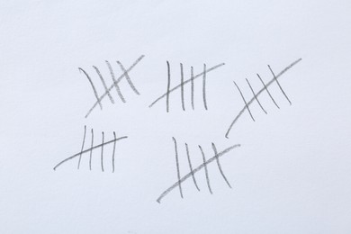 Photo of Counting days by drawing sticks with pencil on white background, closeup