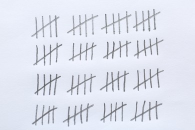 Photo of Counting days by drawing sticks with pencil on white background, closeup