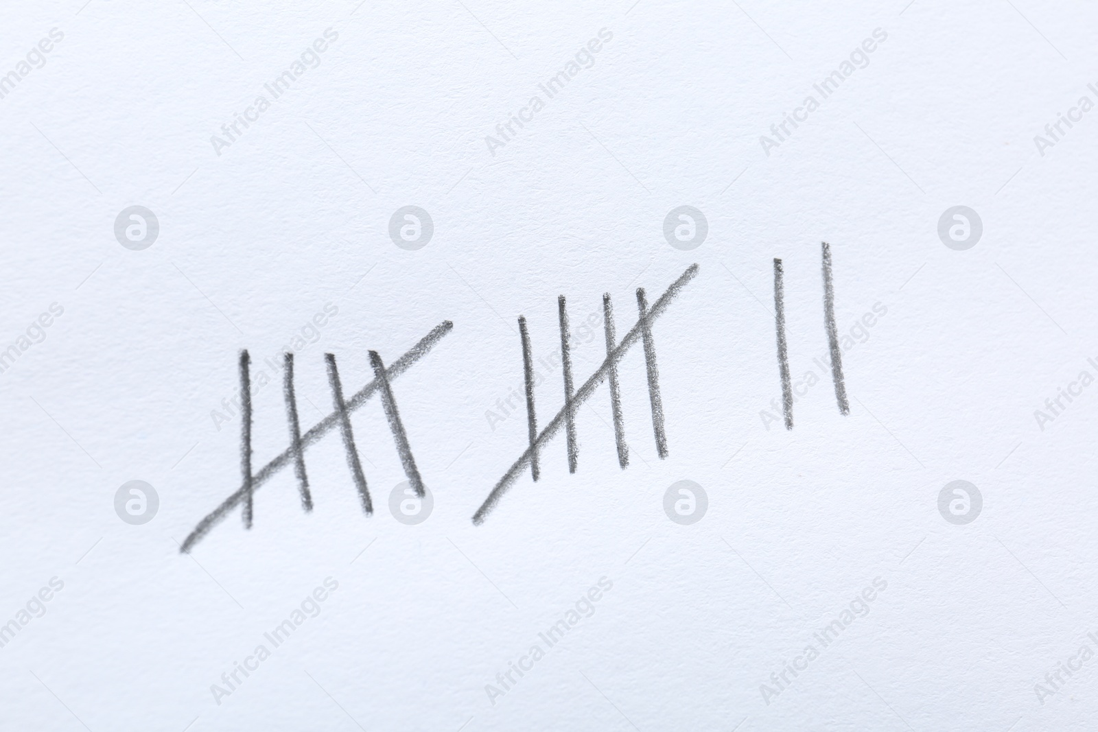 Photo of Counting days by drawing sticks with pencil on white background, closeup