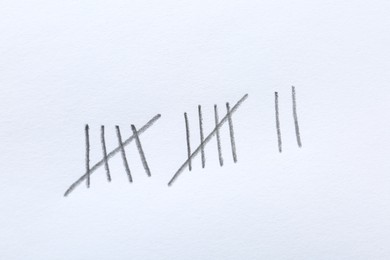 Photo of Counting days by drawing sticks with pencil on white background, closeup