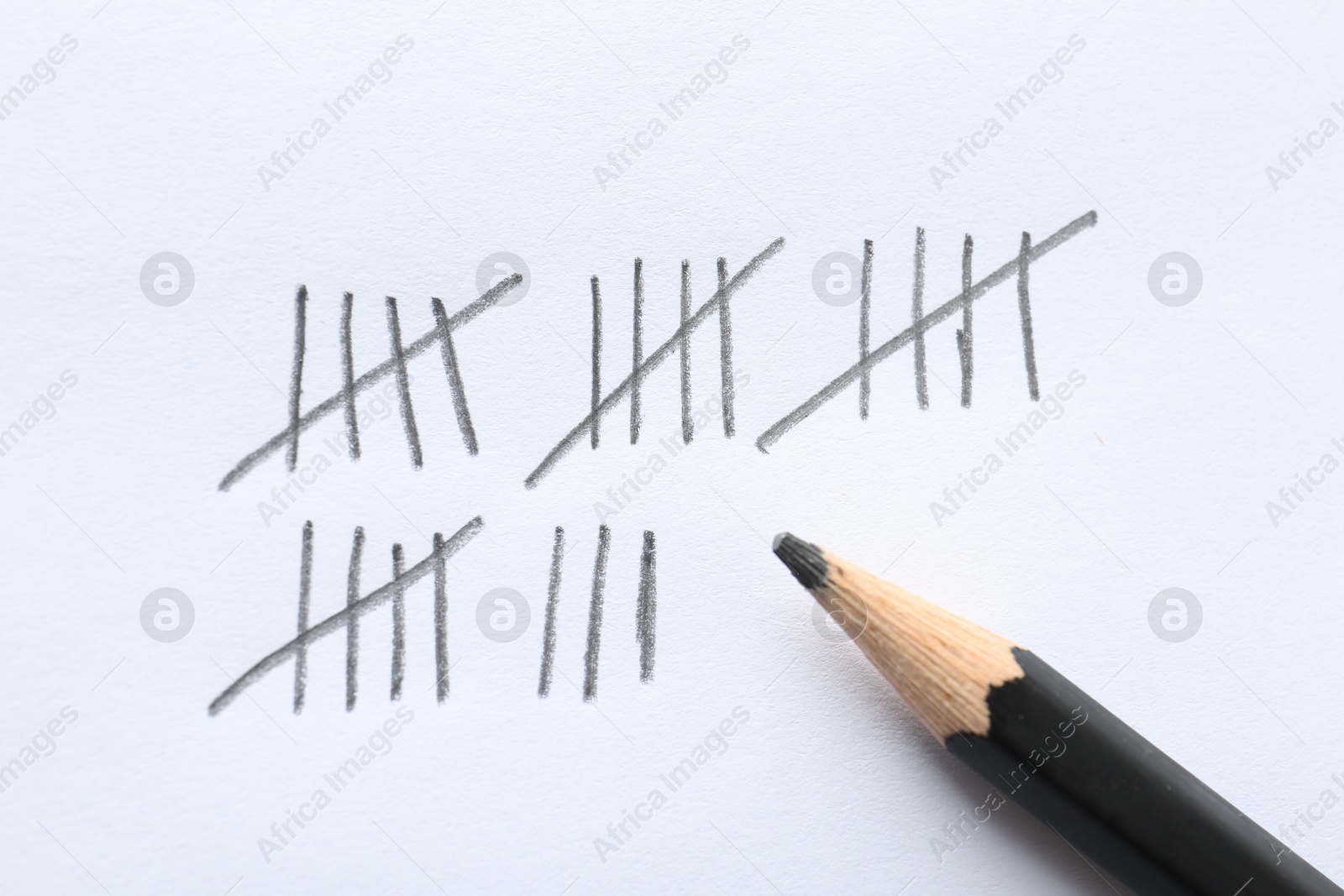 Photo of Counting days by drawing sticks with pencil on white background, closeup