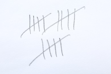 Photo of Counting days by drawing sticks with pencil on white background, closeup