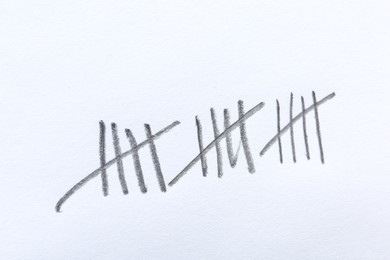 Photo of Counting days by drawing sticks with pencil on white background, closeup