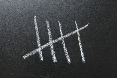 Photo of Counting days by drawing sticks with chalk on blackboard, closeup