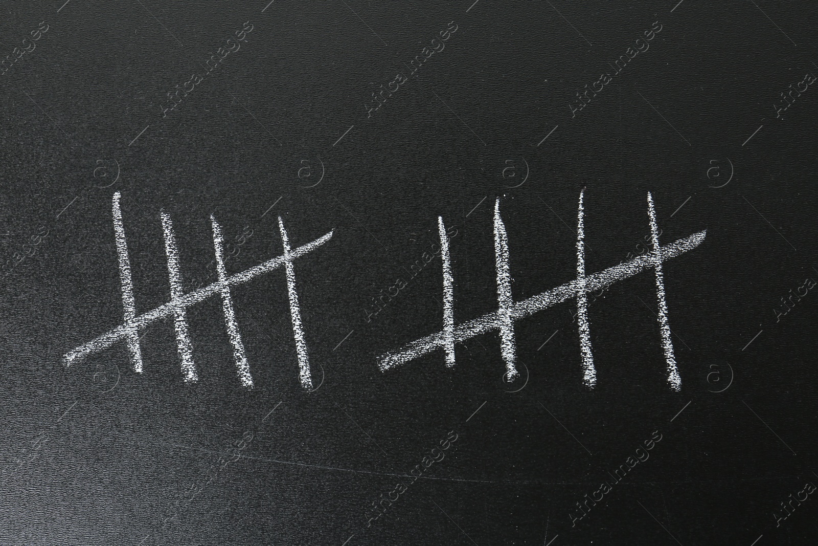 Photo of Counting days by drawing sticks with chalk on blackboard, closeup