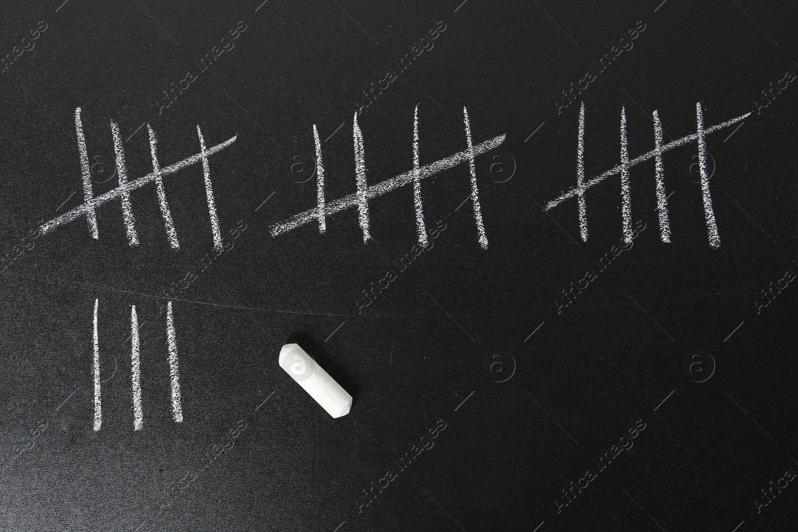 Photo of Counting days by drawing sticks with chalk on blackboard, closeup