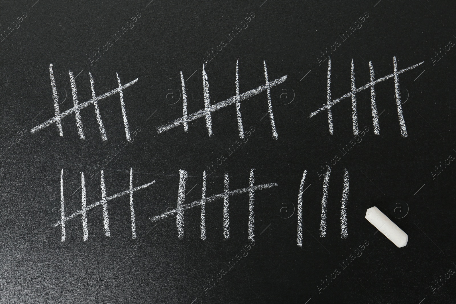 Photo of Counting days by drawing sticks with chalk on blackboard, closeup