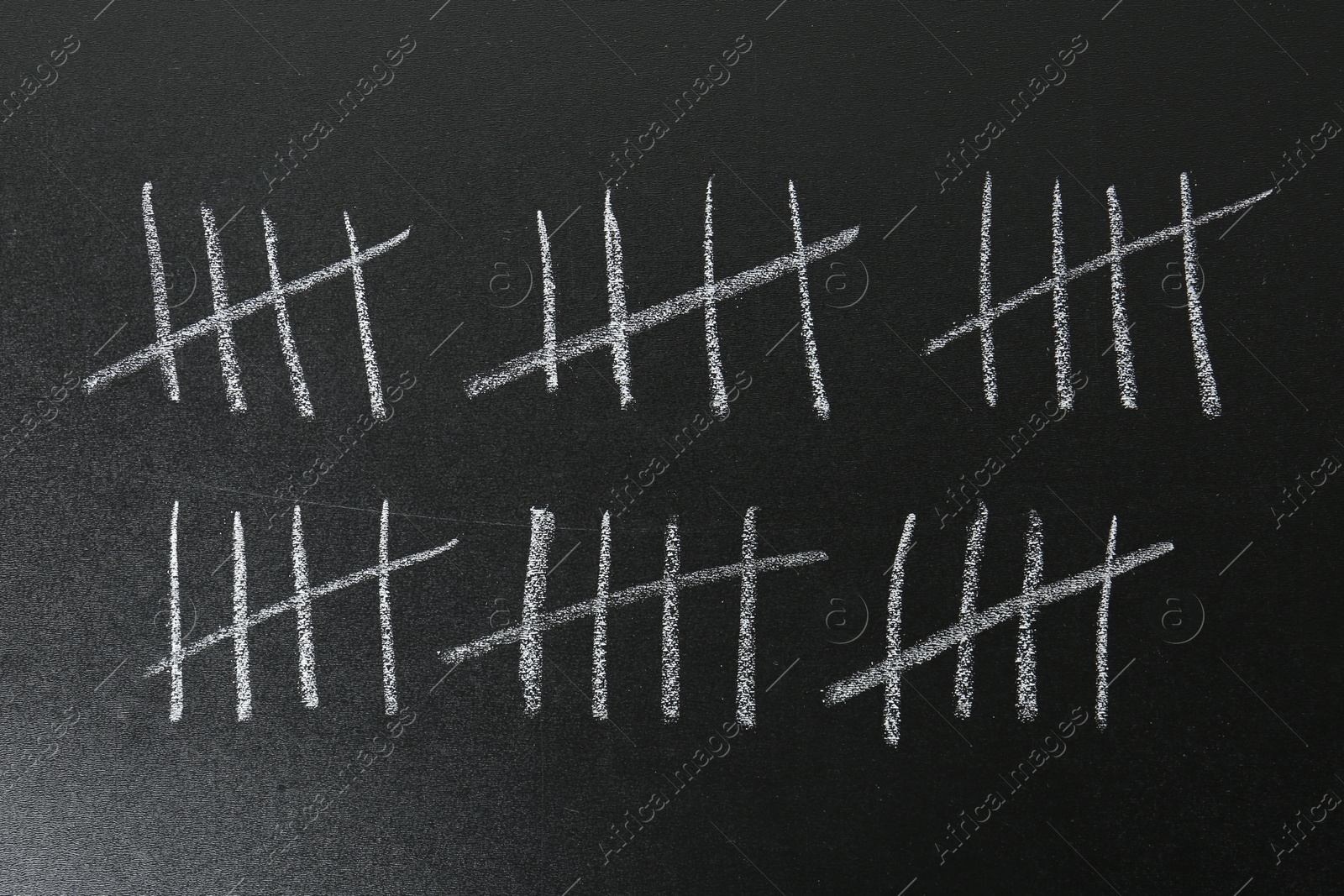 Photo of Counting days by drawing sticks with chalk on blackboard, closeup