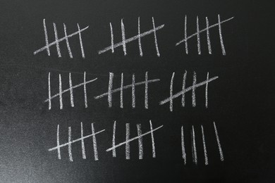 Photo of Counting days by drawing sticks with chalk on blackboard, closeup