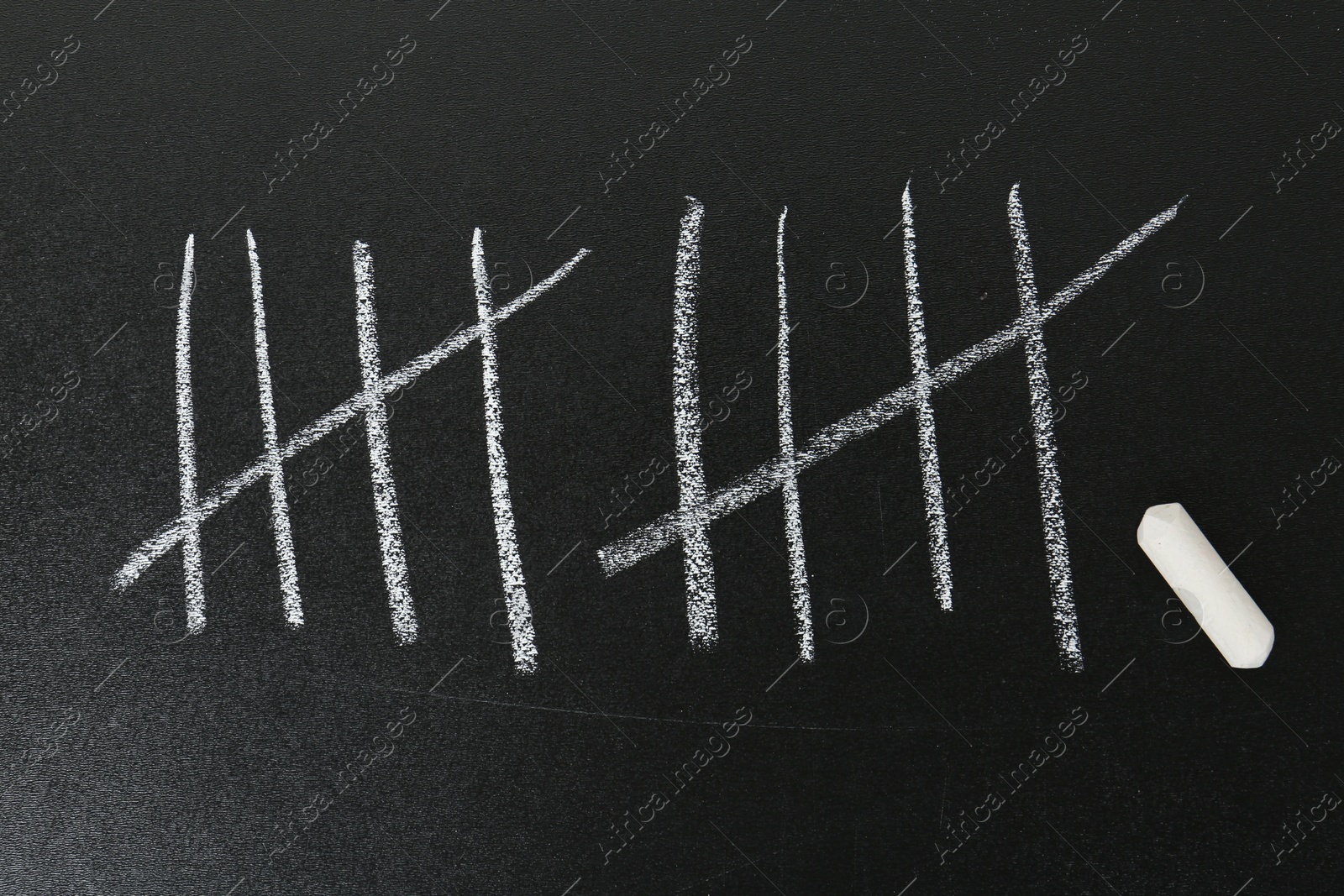 Photo of Counting days by drawing sticks with chalk on blackboard, closeup