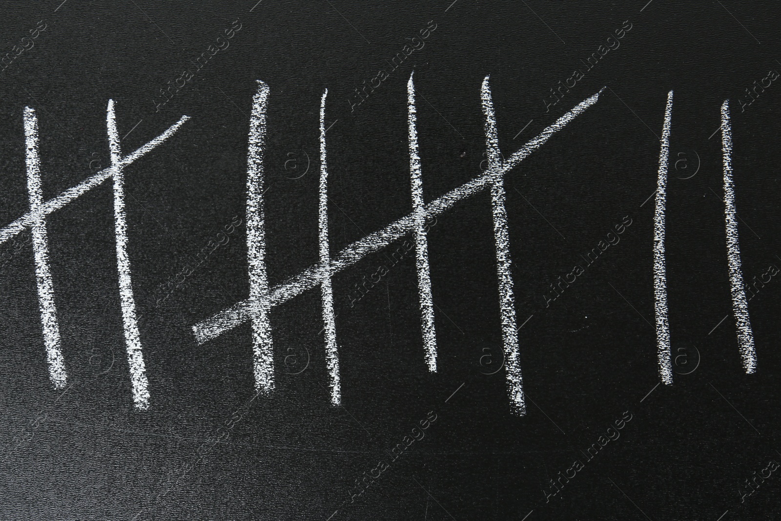 Photo of Counting days by drawing sticks with chalk on blackboard, closeup