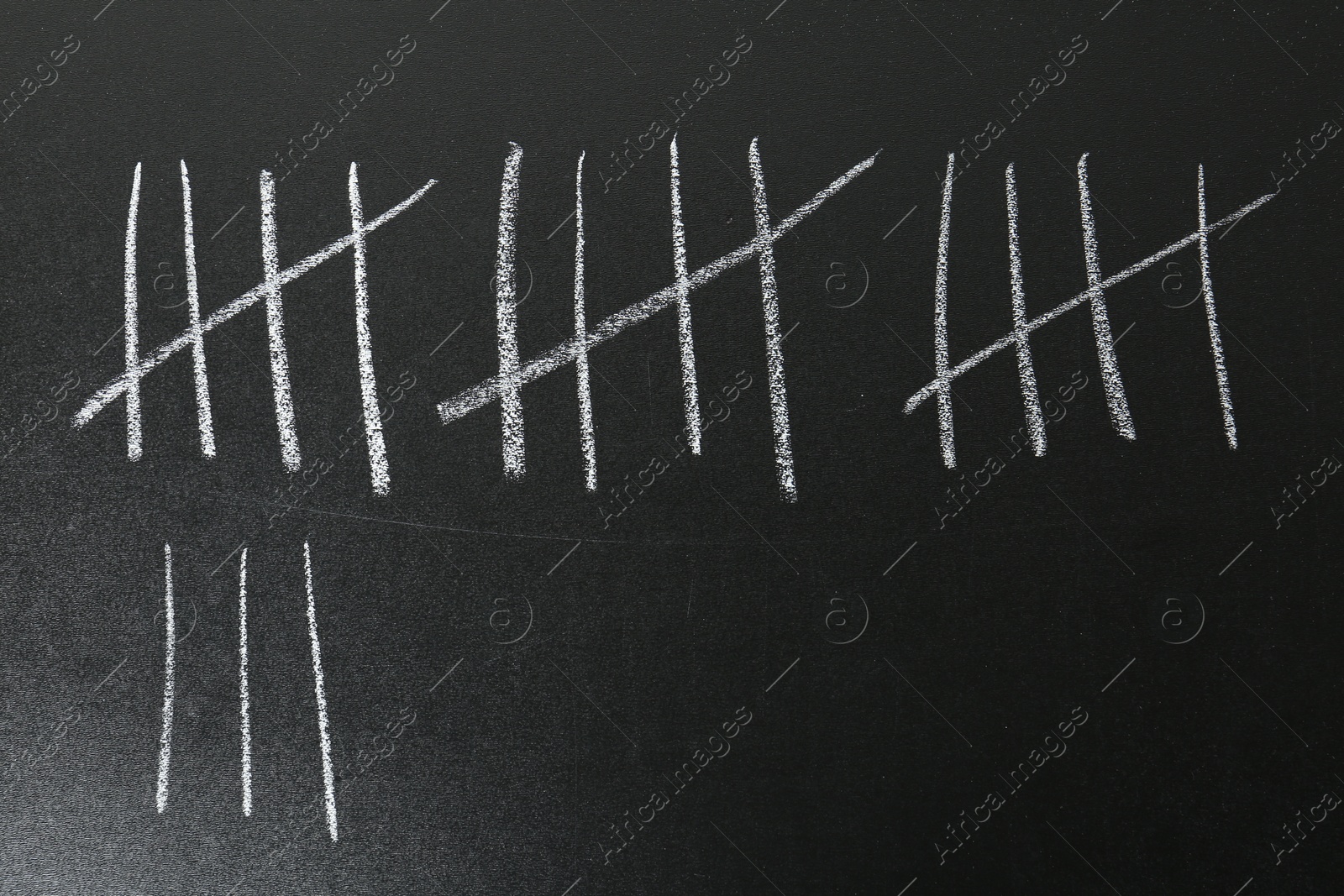 Photo of Counting days by drawing sticks with chalk on blackboard, closeup