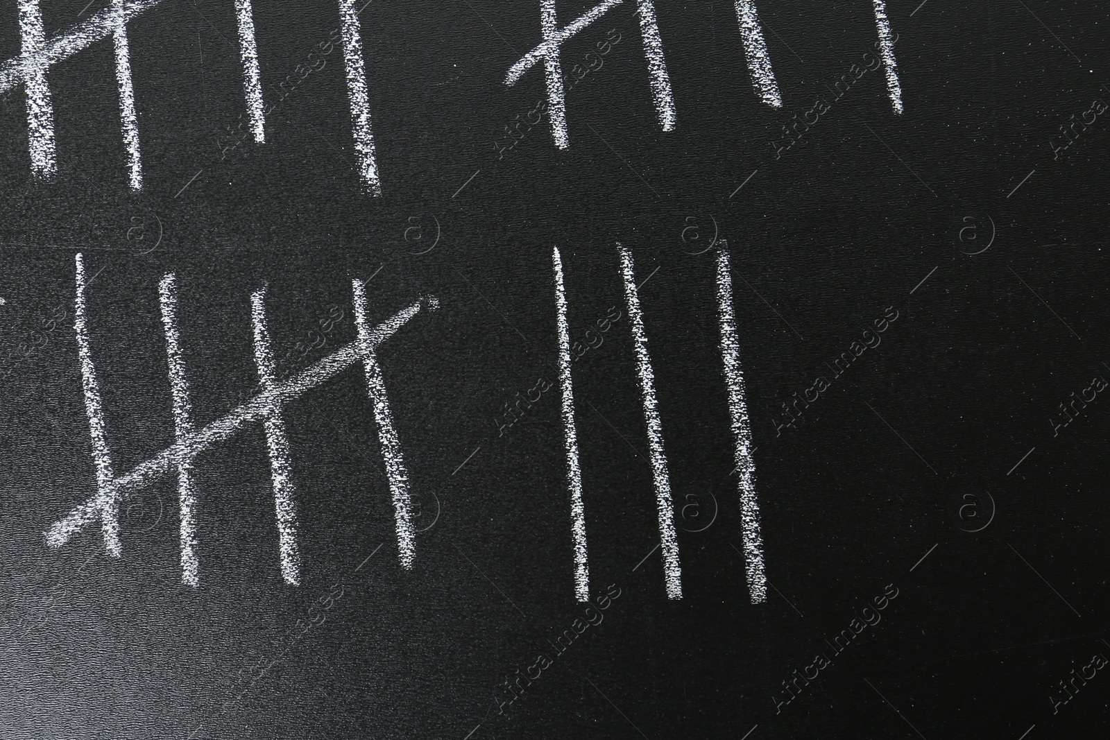 Photo of Counting days by drawing sticks with chalk on blackboard, closeup