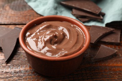 Photo of Tasty pudding and pieces of chocolate on wooden table, closeup