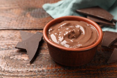 Photo of Tasty pudding and pieces of chocolate on wooden table, closeup