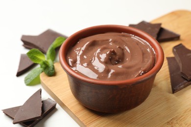 Photo of Tasty pudding, mint and pieces of chocolate on white table, closeup