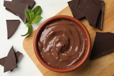 Photo of Tasty pudding, mint and pieces of chocolate on white table, flat lay