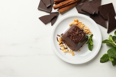 Photo of Tasty chocolate pudding with peanuts and mint on white table, flat lay. Space for text