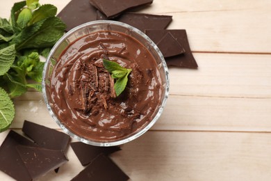 Photo of Tasty pudding with mint and pieces of chocolate on white wooden table, flat lay. Space for text