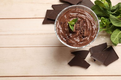 Photo of Tasty pudding with mint and pieces of chocolate on white wooden table, flat lay. Space for text