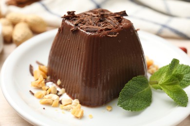 Tasty chocolate pudding with peanuts and mint on white table, closeup