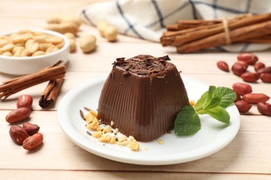 Photo of Tasty chocolate pudding with peanuts and mint on white wooden table