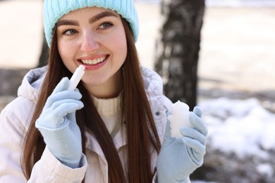 Beautiful young woman applying lip balm on winter day