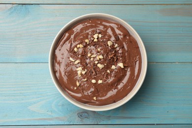 Photo of Tasty chocolate pudding in bowl on light blue wooden table, top view