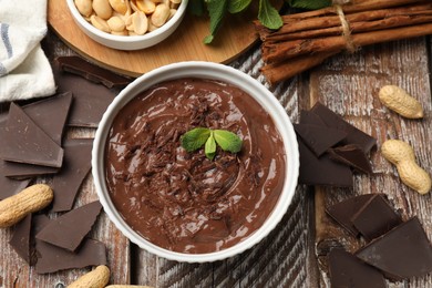 Photo of Tasty chocolate pudding in bowl and ingredients on wooden table, flat lay