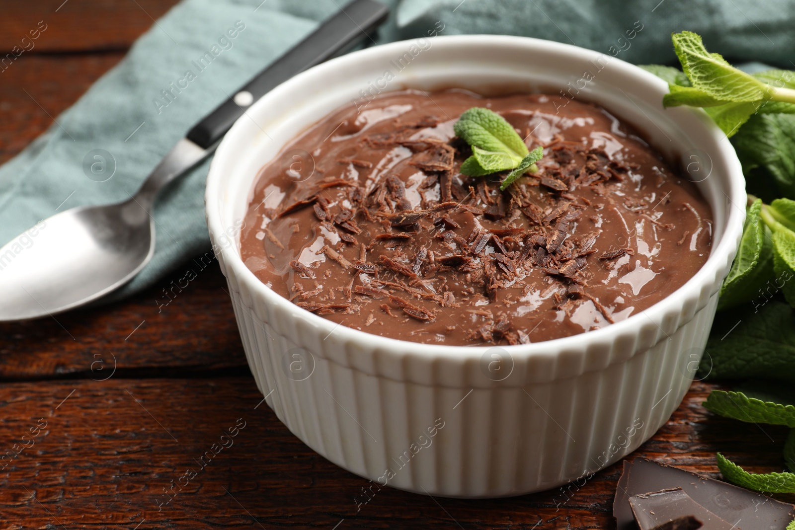 Photo of Tasty chocolate pudding in bowl on wooden table, closeup