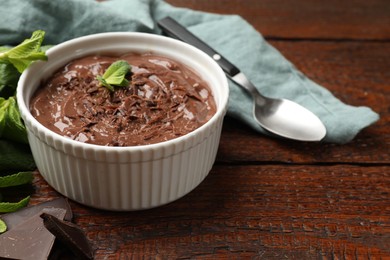 Photo of Tasty chocolate pudding in bowl on wooden table, closeup