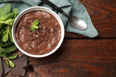 Photo of Tasty chocolate pudding in bowl served on wooden table, flat lay