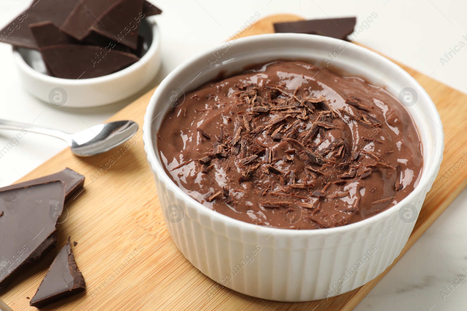 Photo of Tasty chocolate pudding in bowl served on white table, closeup