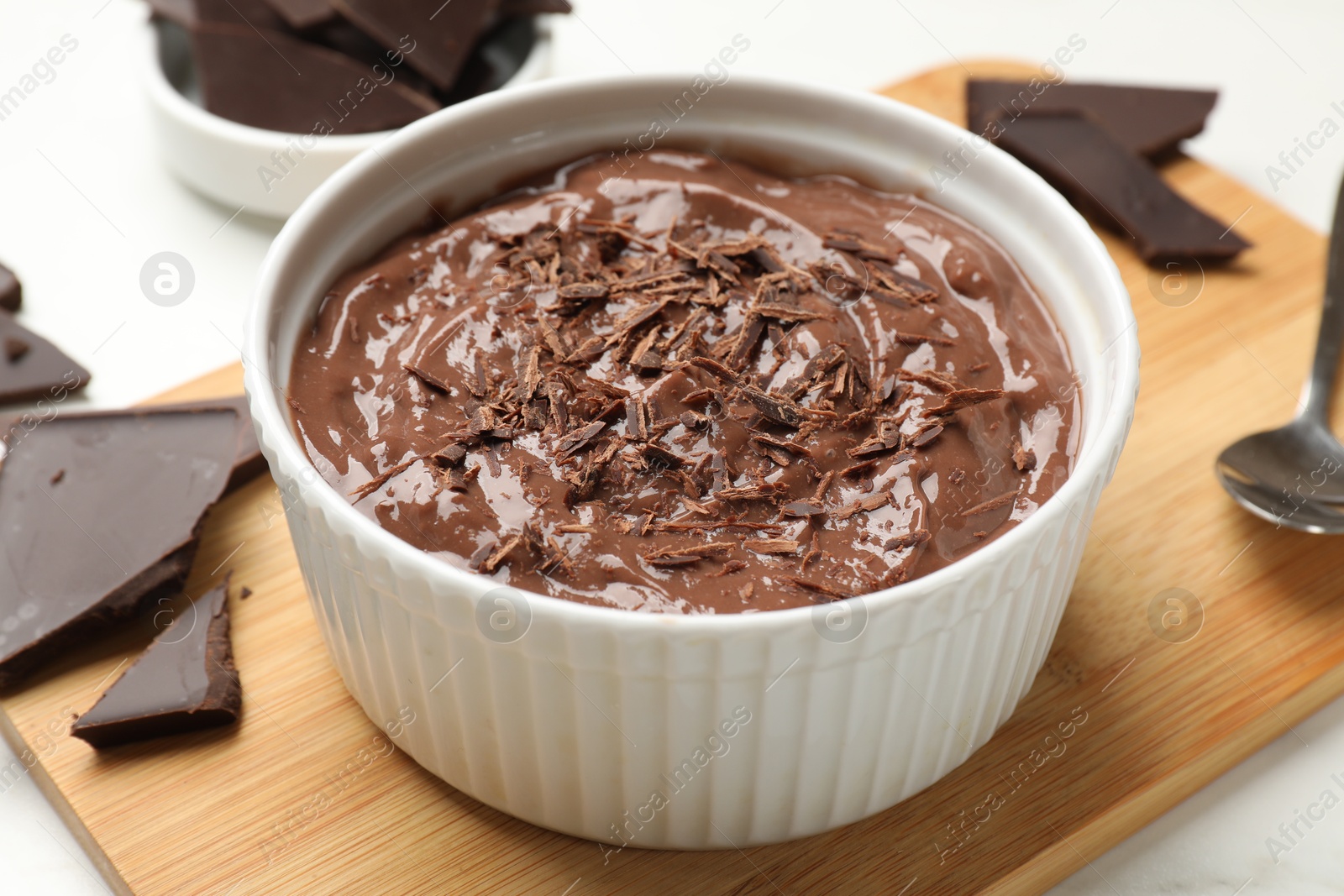 Photo of Tasty chocolate pudding in bowl served on white table, closeup